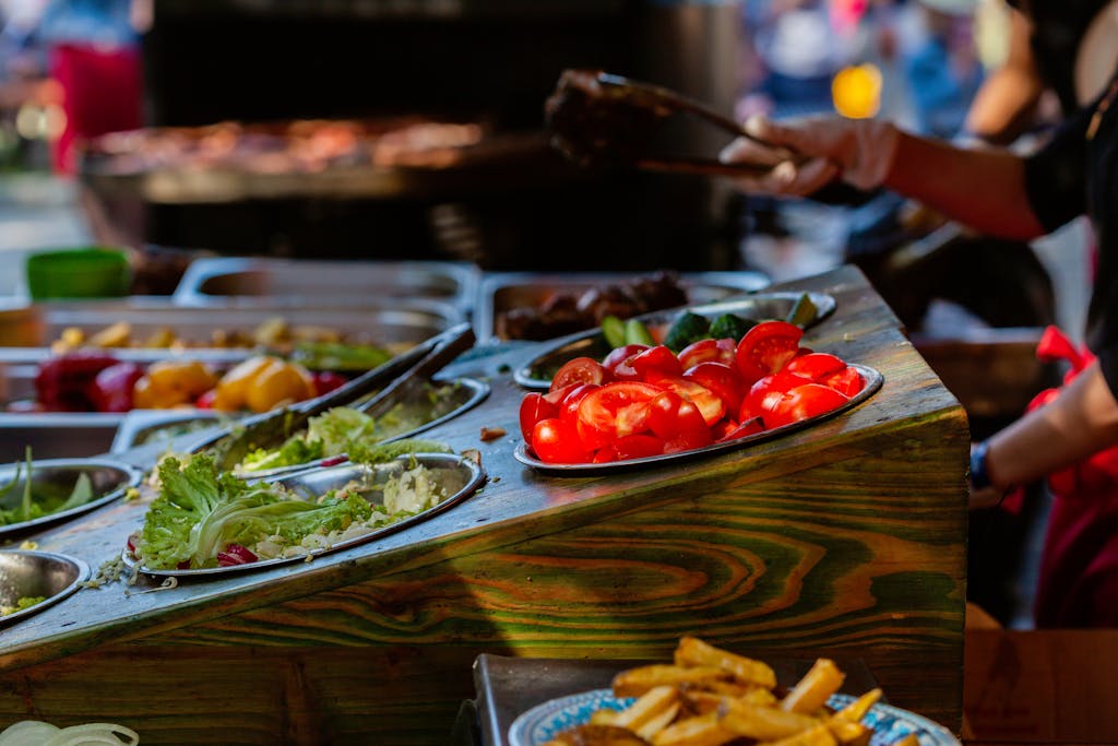 Colorful display of fresh vegetables and ingredients at an outdoor food market stall.